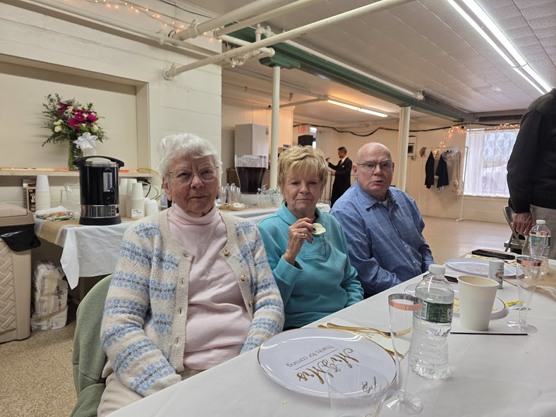 Three members seated together at a decorated lunch table